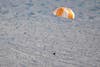 kapsül takılı beyaz ve turuncu bir paraşüt gökten kumlu bir manzaraya doğru uçuyor